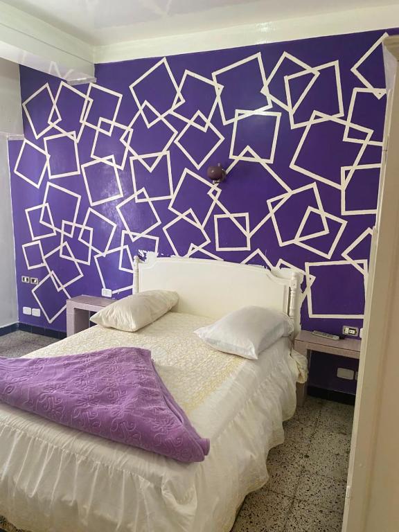 a bedroom with a purple and white wall with a bed at Hôtel Dar Massmoudi in Tunis