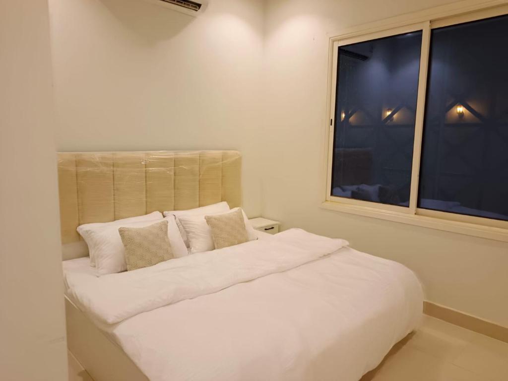 a white bed in a room with a window at روشيلا in Al Majma'ah