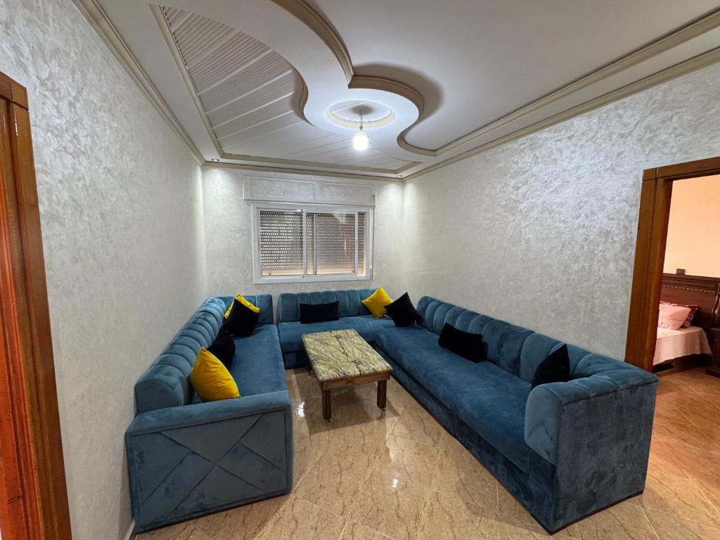 a living room with a blue couch and a table at Larache City Apartment in Larache