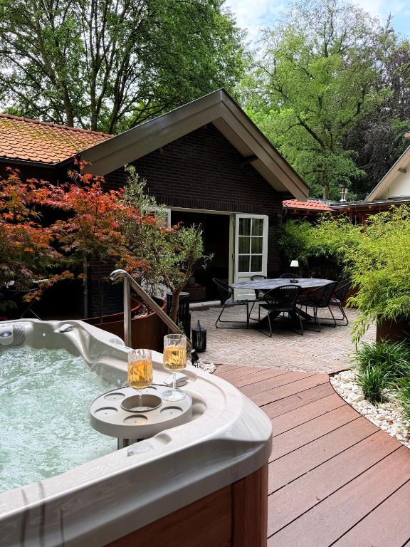 a hot tub on a wooden deck with a table at Berg en Bos Suite met luxe jacuzzi in Apeldoorn