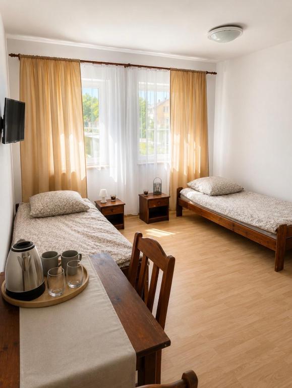 a hotel room with two beds and a table with cups on it at Pensjonat Rowy Blisko Morza in Rowy
