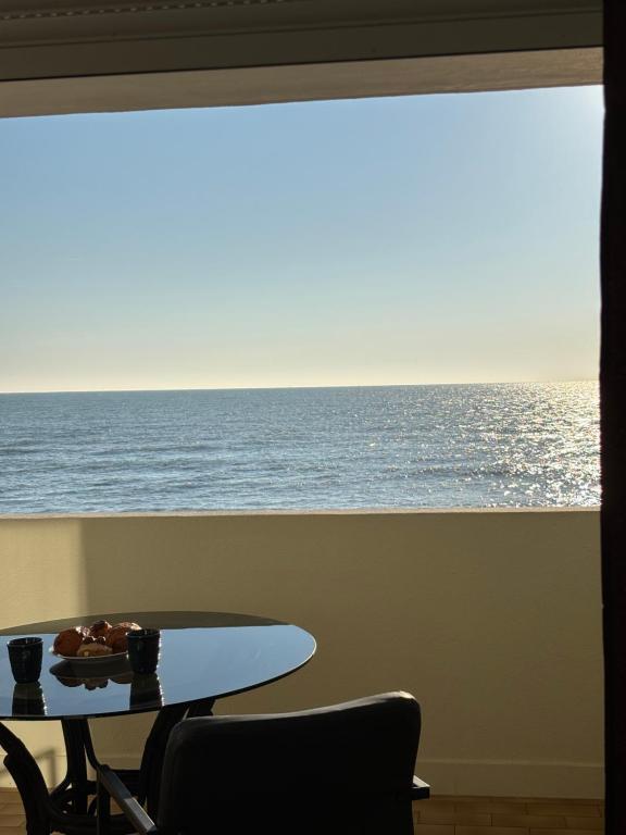 a table and chairs in front of a window with the ocean at Le TAHITI in Frontignan