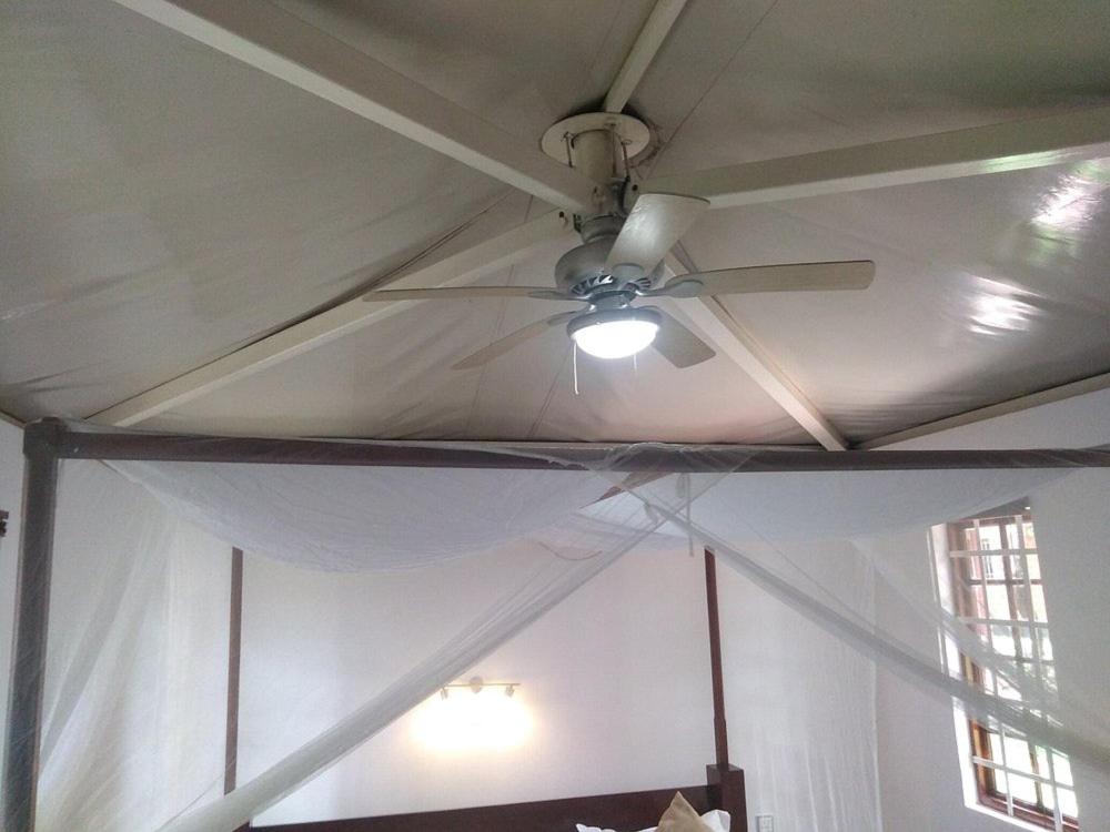 a ceiling fan in a room with a white curtain at Mara Son Camp in Maasai Mara National Reserve