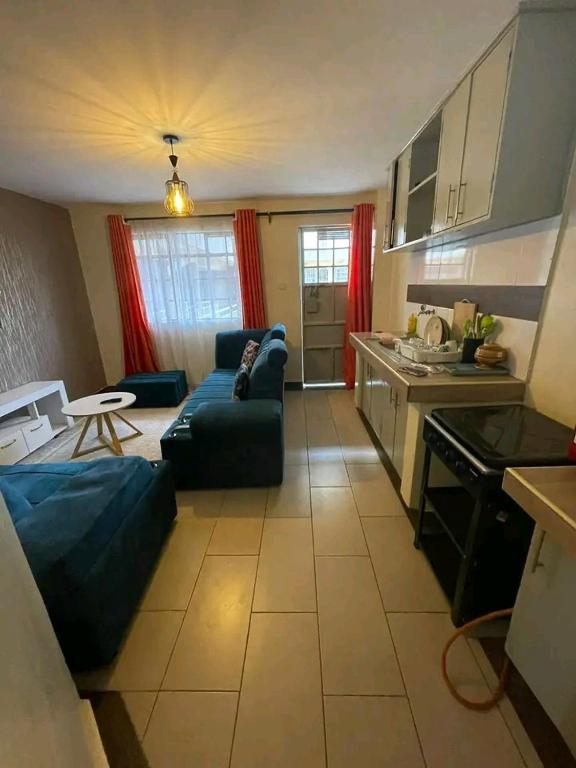 a living room with a blue couch and a kitchen at Bulleys BNB in Thika