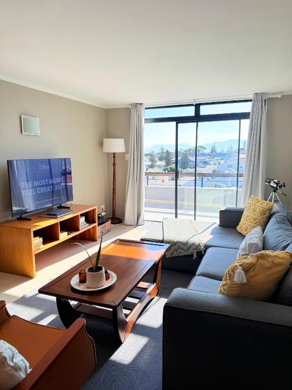 a living room with a blue couch and a tv at SaltySky Penthouse in Gansbaai