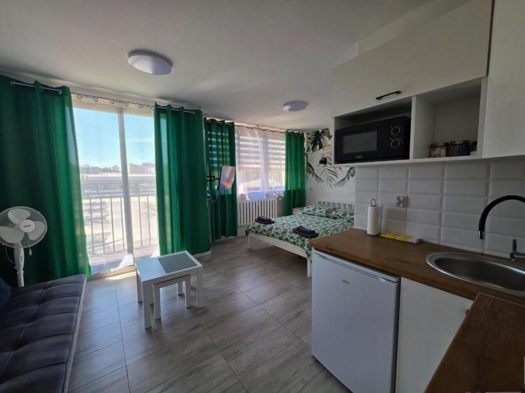 a kitchen and living room with green curtains and a couch at Apartamenty Częstochowa in Częstochowa