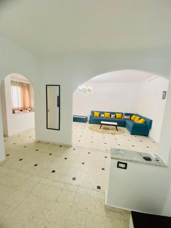 a living room with a blue couch and a table at Appart AL MARAII - Familles seulement in Beni Khiar