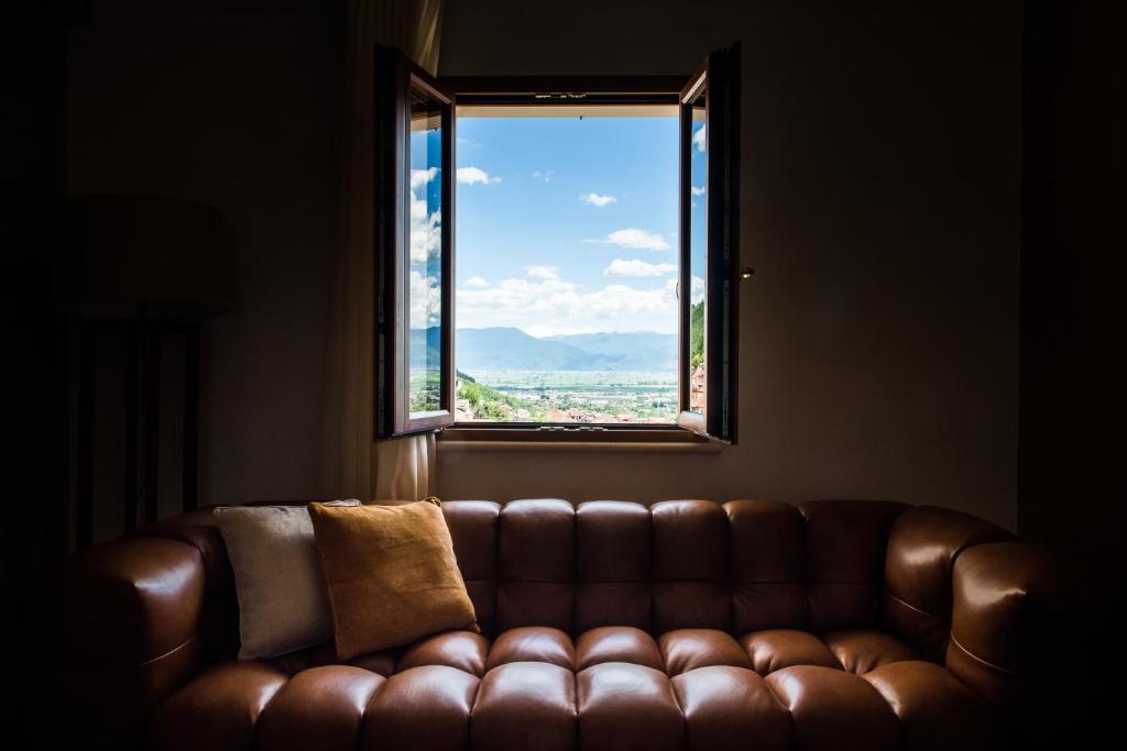 a brown couch sitting in a room with a window at Dimore Abruzzo - Borgo 27 in Celano