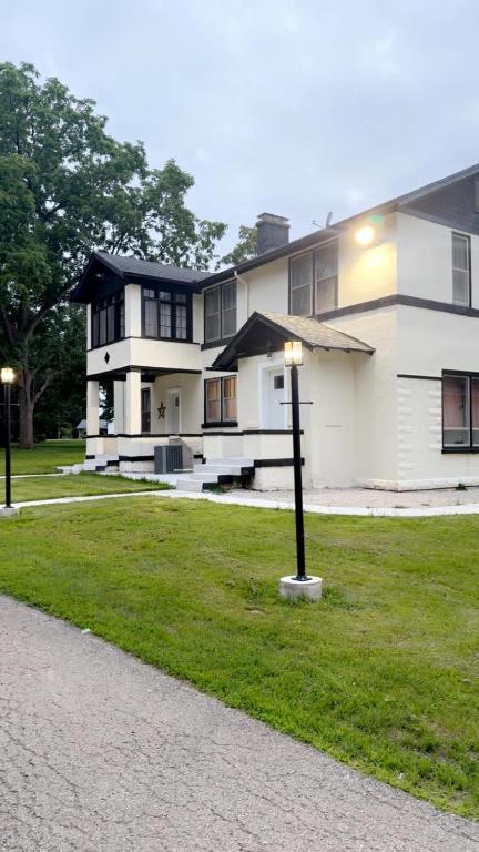 a white building with a street light in the grass at A J House in Plano