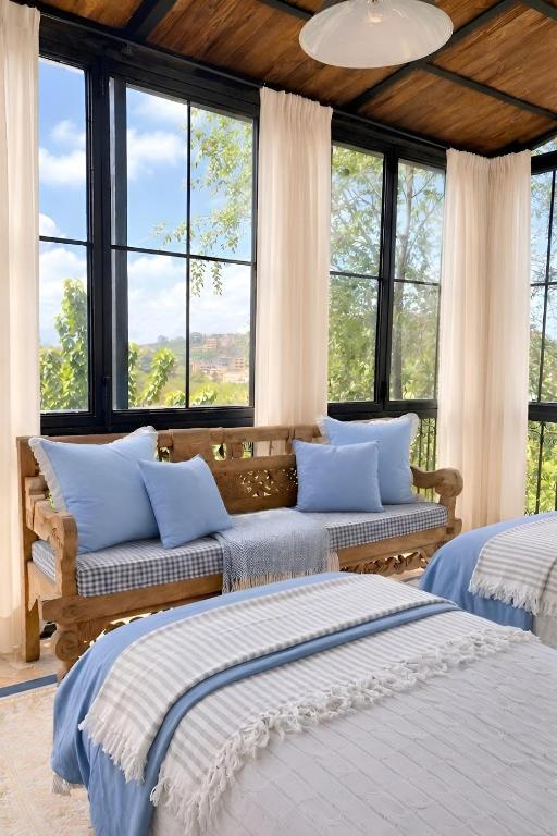 two beds in a room with large windows at Laklouk 1808 Lodge by Hansa in ‘Ayn aş Şalīb