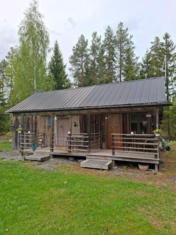 a large wooden cabin with a porch in the grass at Raju - Guest House in Seinäjoki