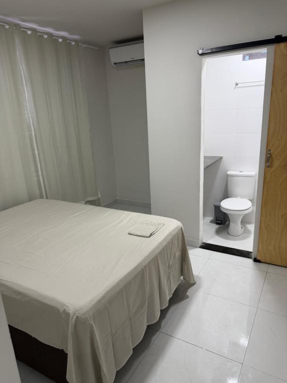 a white bedroom with a bed and a toilet at Hostel do moreno in Vila Velha