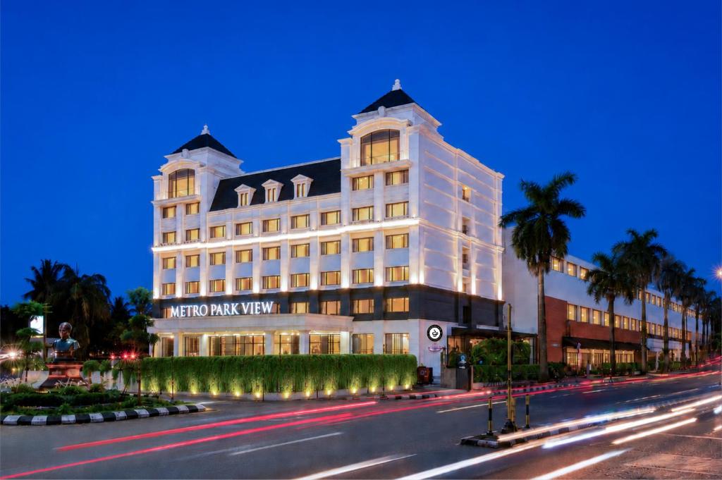a large white building on a city street at night at Metro Park View Hotel Kota Lama Semarang in Semarang