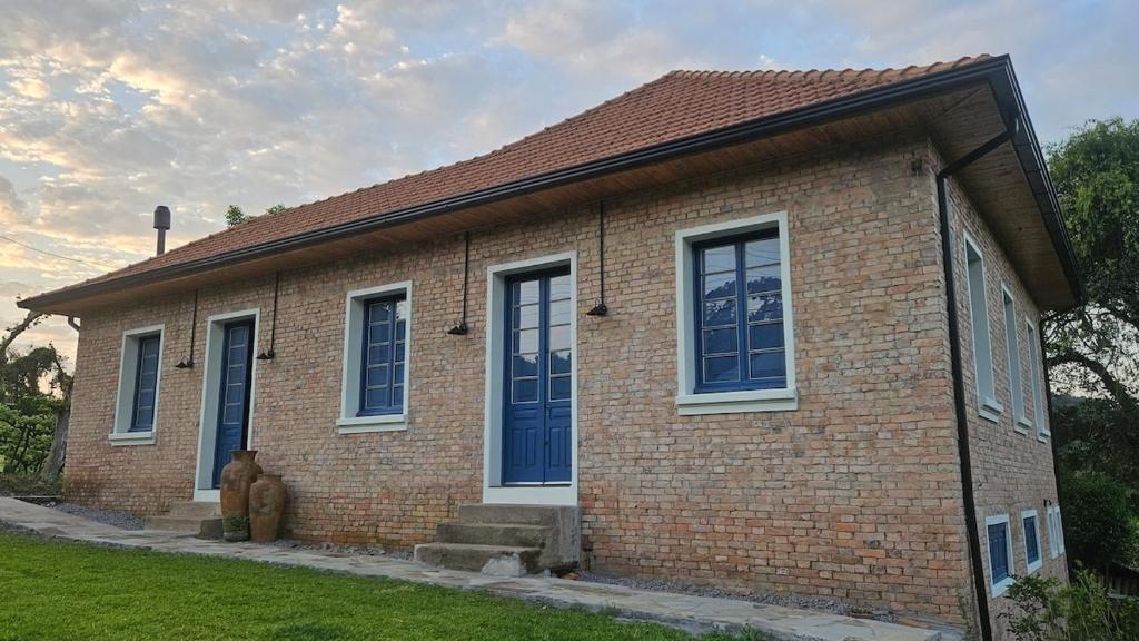 a brick house with blue doors and windows at Casa 80 in Monte Belo