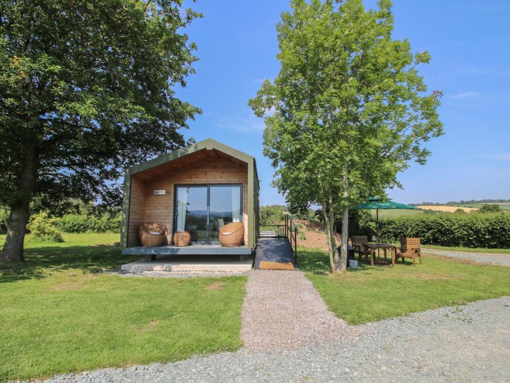 a small shed with a window and a tree at Leafy Oaks Cabin in Much Wenlock
