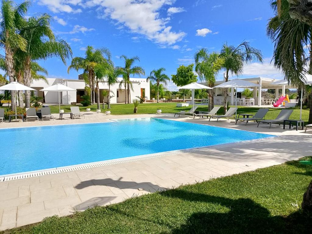 a swimming pool with chairs and umbrellas in a yard at Tenuta Espada Gallipoli in Gallipoli