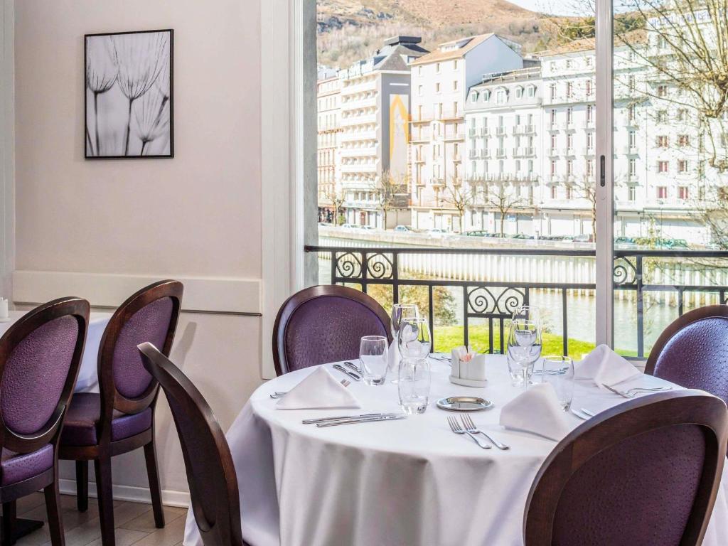 a dining room with a table and chairs and a window at Mercure Lourdes Impérial in Lourdes
