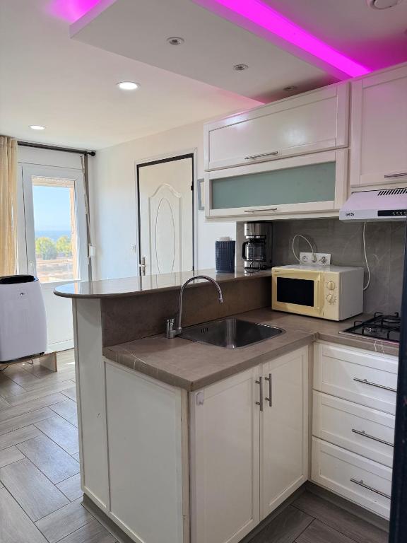 a kitchen with a sink and a microwave at Casa Mare Oureah in Mazagran