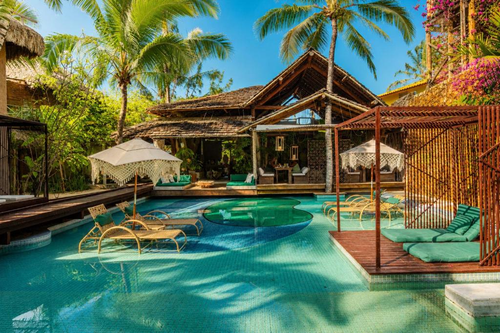 a pool at a resort with chairs and umbrellas at Aloha Village Hotel in Icaraí