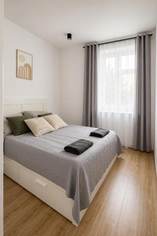 a white bedroom with a large bed and a window at Apartamenty na Witosa in Nowa Sól