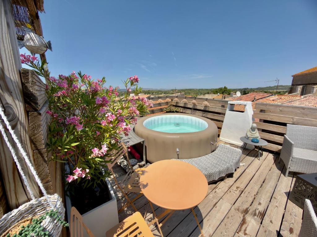 a patio with a hot tub on a deck with flowers at Les Anges de Sigean, Chambres d'hôtes de Luxe,Rooftop Panoramique avec Jacuzzi in Sigean