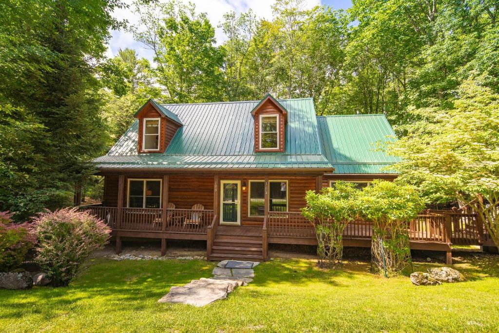 a log cabin with a green roof and a yard at Lei Lei Mountainstay in Beech Mountain