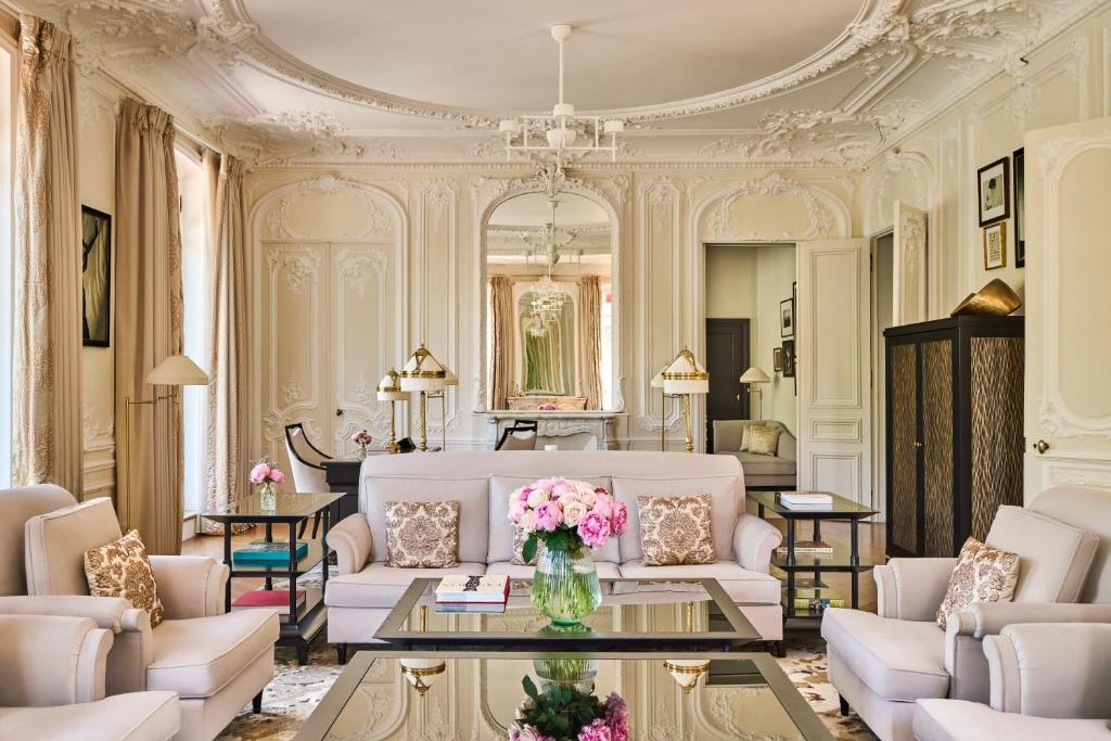 a living room with white furniture and pink flowers at Hôtel Fouquet's Paris in Paris