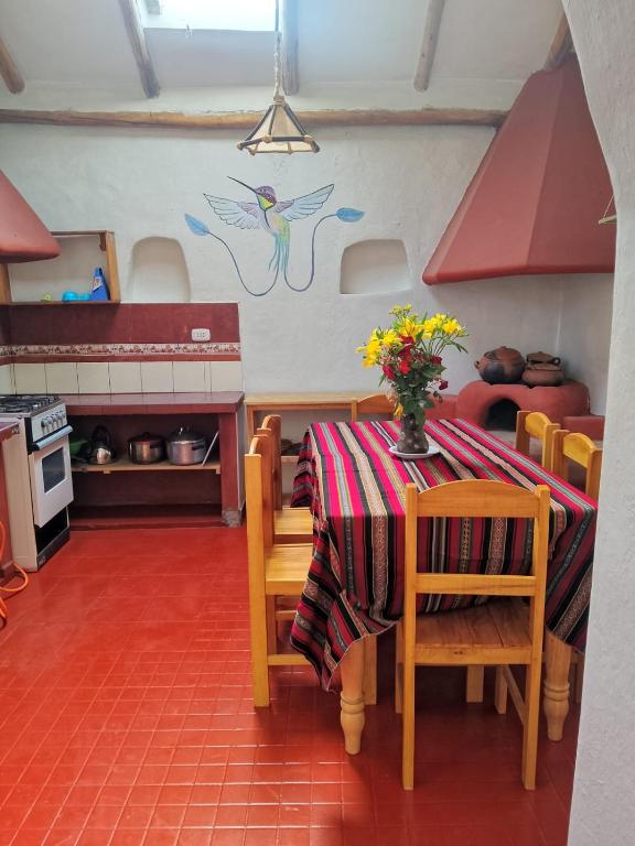a kitchen with a table with a vase of flowers on it at El molle in Pisac
