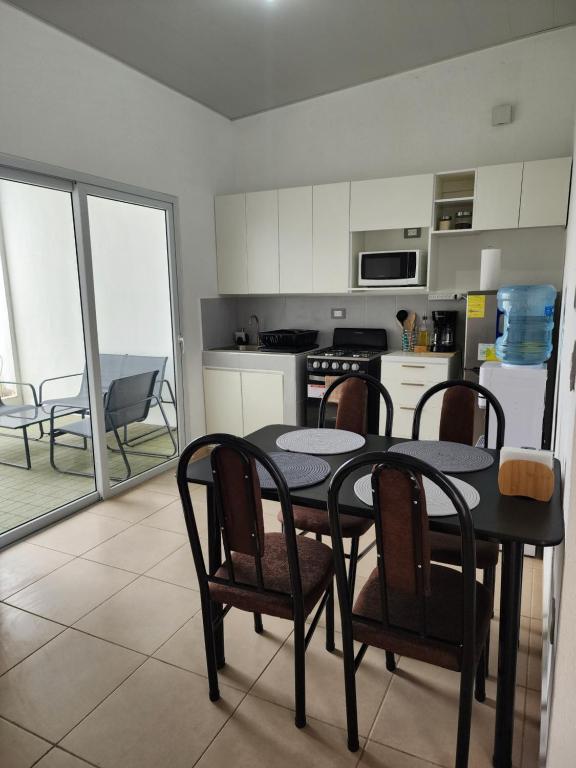 a kitchen with a black table and chairs and a kitchen with a kitchen at Marsella Rest House in Sitio del Niño