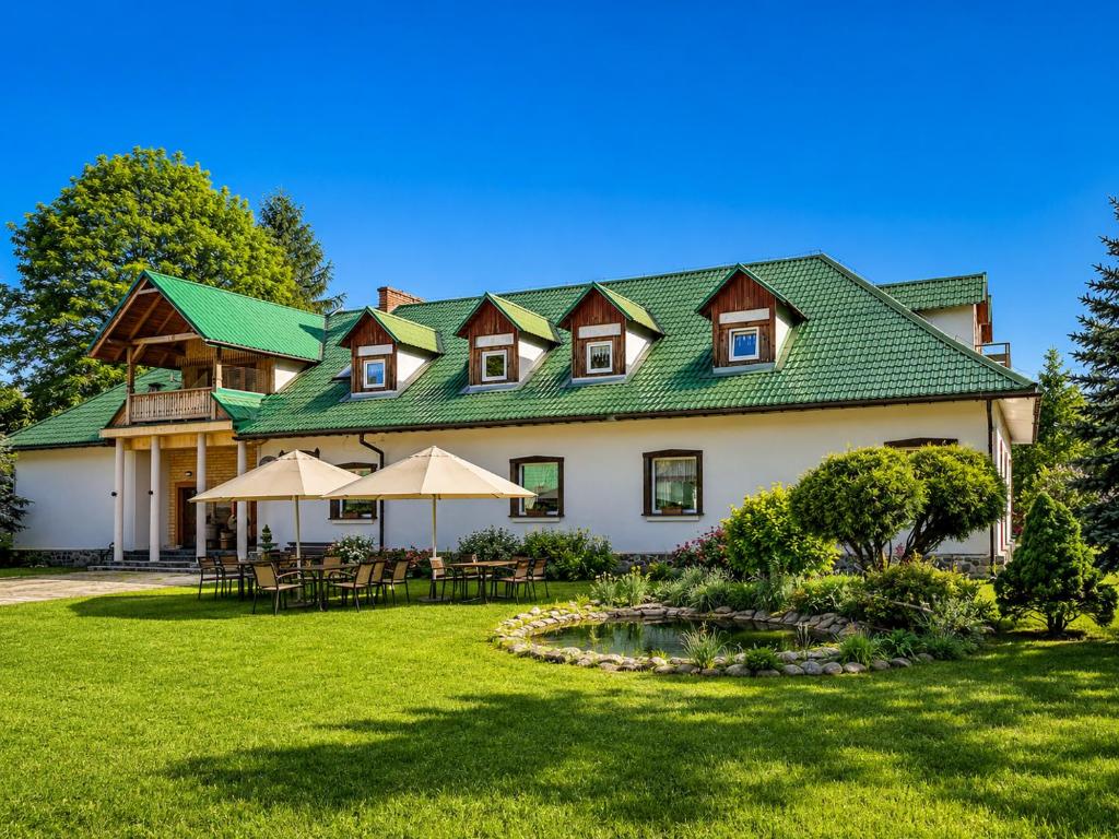 a large house with a green roof on a lawn at Latarnia Wagabundy Bieszczady in Wola Michowa