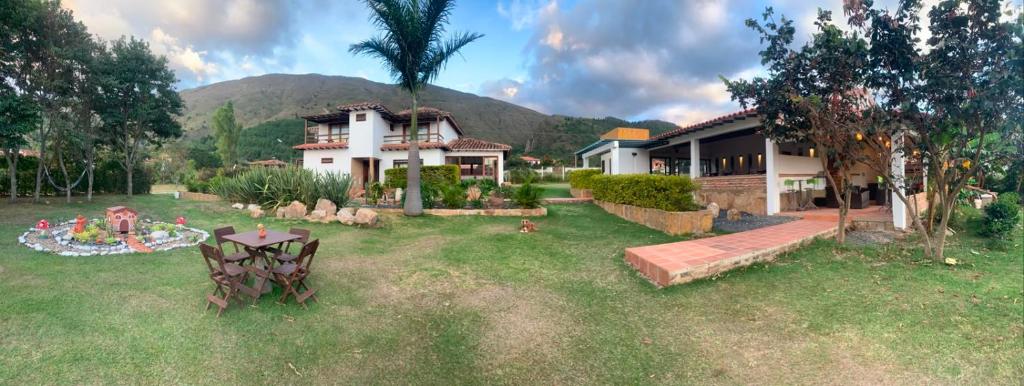 a house with a table in front of a yard at hotel torres del viento in Villa de Leyva