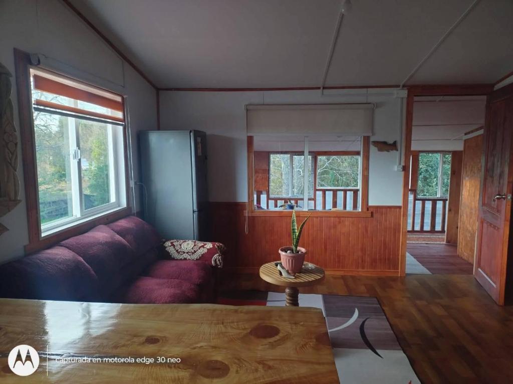 a living room with a purple couch and a table at Departamento con tinaja in Llanquihue