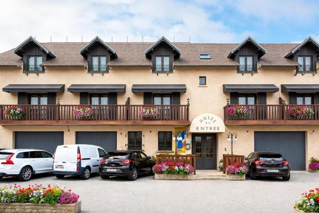 a large building with cars parked in front of it at Hôtel le Tilleul in Corps