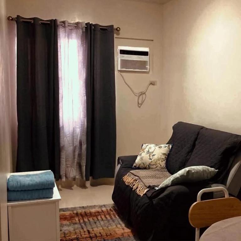 a living room with a black couch and a window at Linear Space at Soleia Butuan Unit G in Butuan