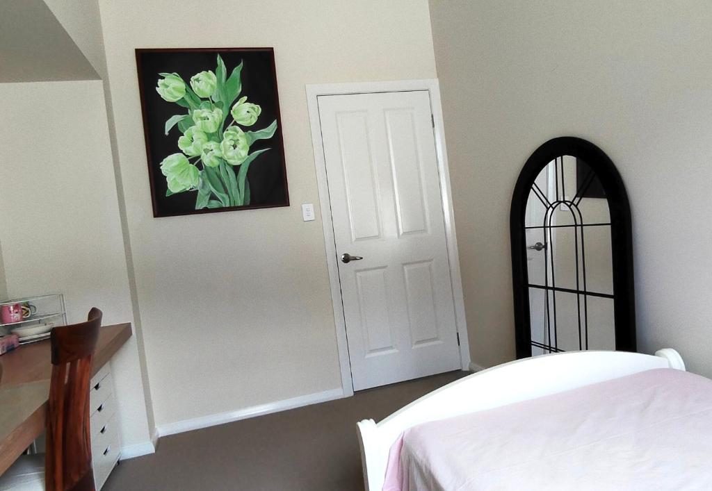 a bedroom with a white door and a picture of flowers at The Fifth Season in Unanderra