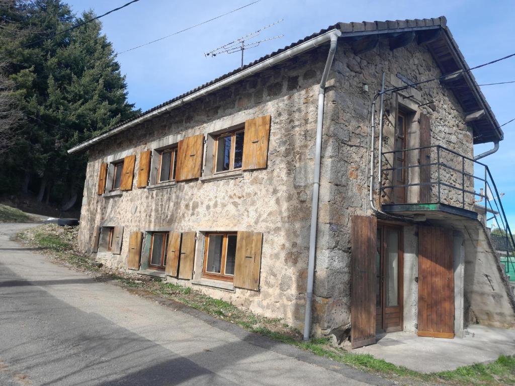 an old stone building with wooden windows and a balcony at Maison rustique in Devesset