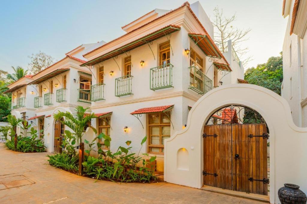 a large white house with a wooden door at Villa Eden 3BHK in Assagao