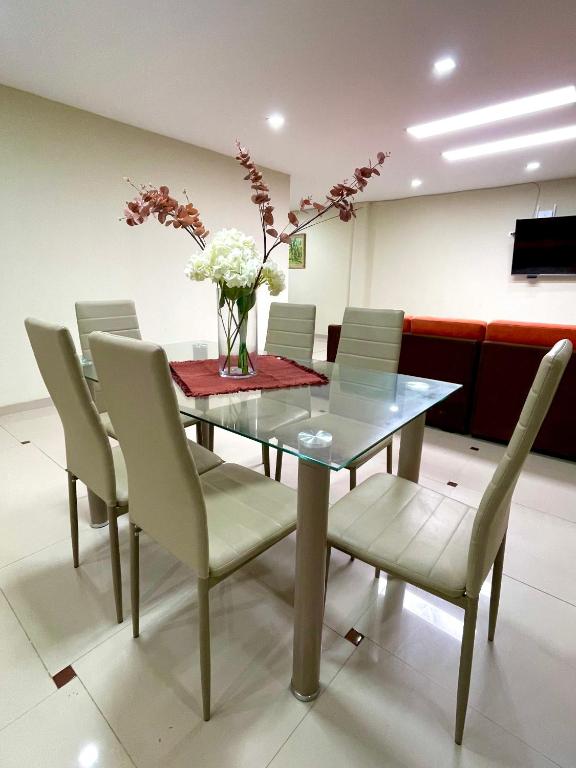 a dining room table with chairs and a vase of flowers at La casa de Ferro in Piura