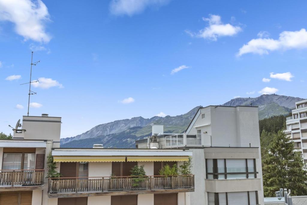 an apartment building with mountains in the background at Appartement central et confortable in Crans-Montana