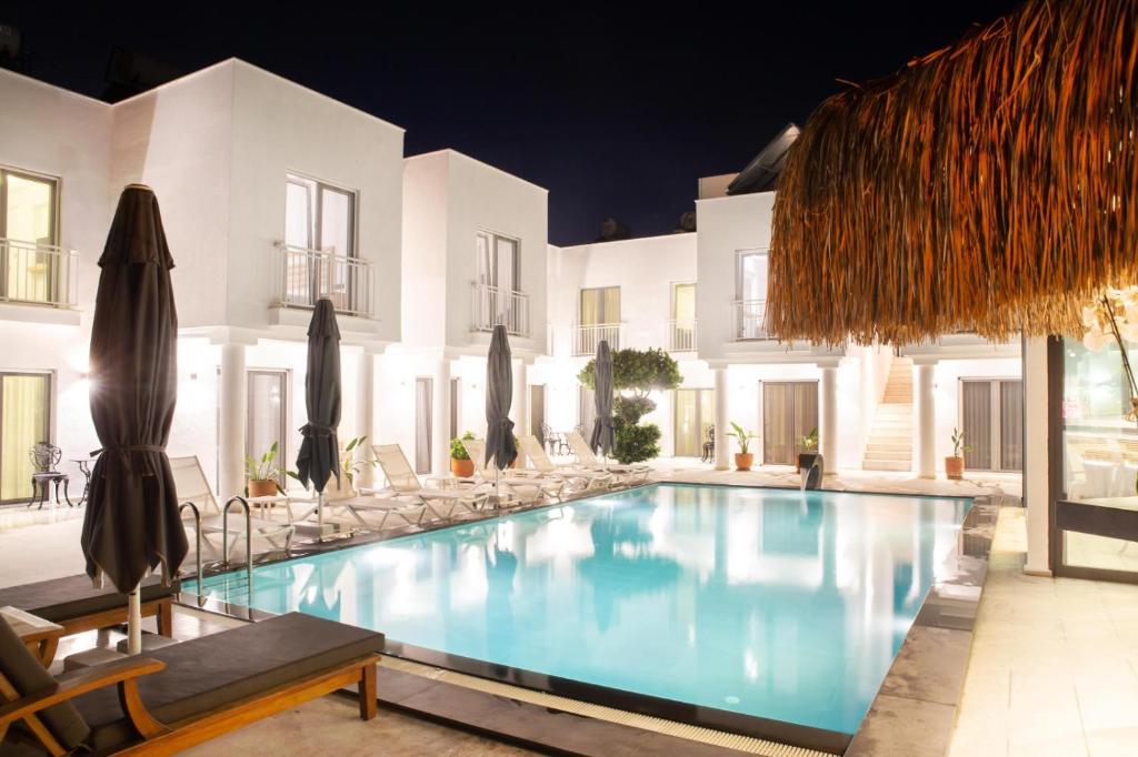 a pool with chairs and umbrellas next to a building at Sör Apart Otel in Bodrum City