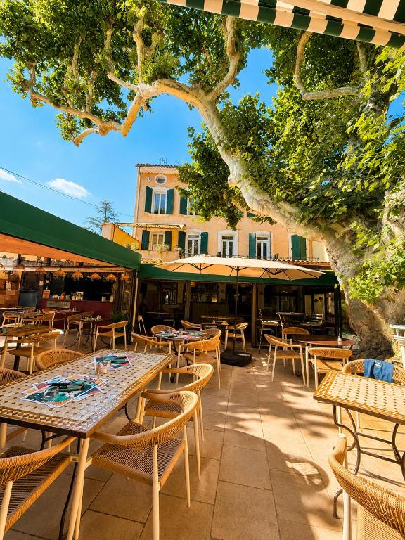 a patio with tables and chairs and a building at Le Grand Hotel Restaurant in Aups