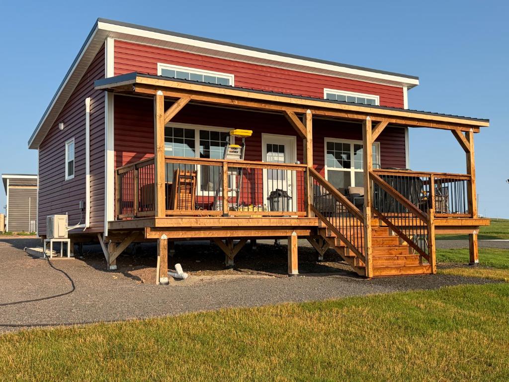 a house with a large porch and a deck at Down East Cabins Ltd in Tracadie