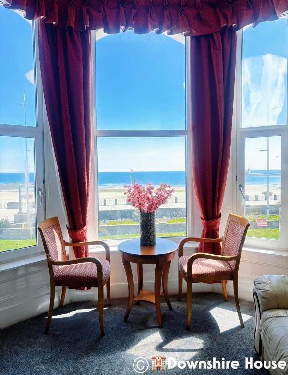 a living room with a table and two chairs and a window at Downshire House in Douglas