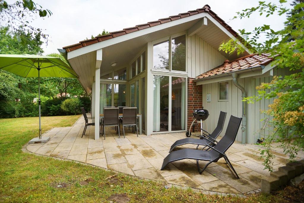 a house with a patio with chairs and an umbrella at Haus E 1 in Röbel