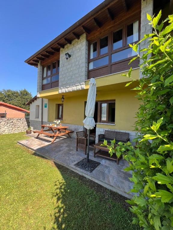 a house with a patio with an umbrella and a table at Gestiona2R - Casa Dos Carmenes, caminando a la playa, ideal familias in Llanes