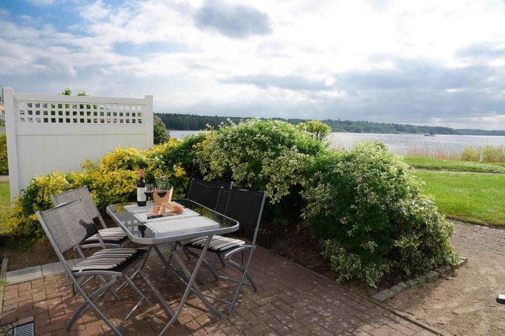 a table and chairs on a patio with a view of the water at Am Seeufer 59 Fewo 1 in Waren