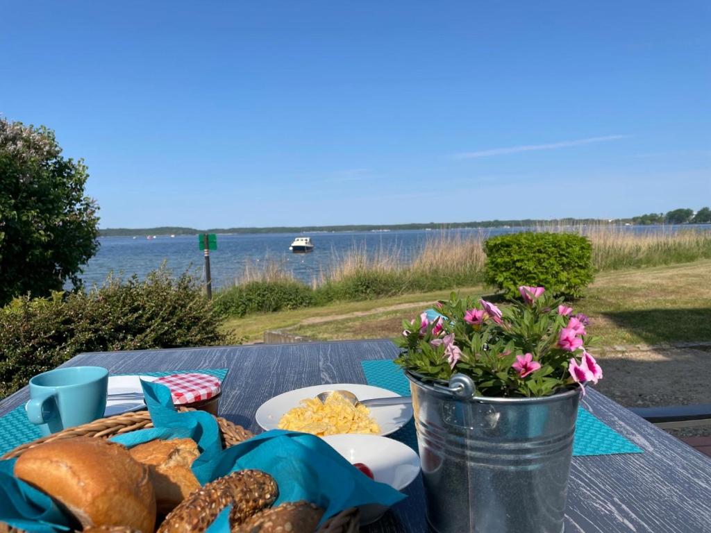a picnic table with food and a bucket of flowers at Am Seeufer 59a Fewo 9 in Waren
