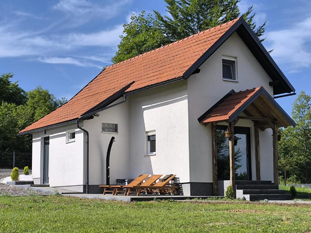 a white building with benches in front of it at Holiday House Štrbački buk in Donji Lapac