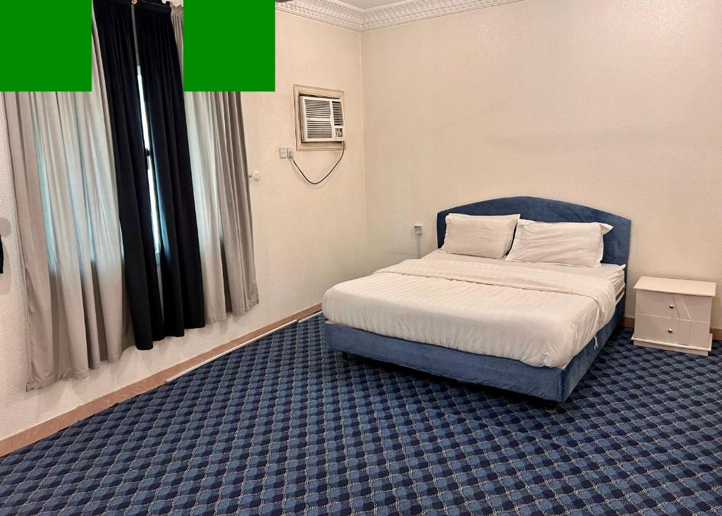 a bedroom with a bed with a blue headboard at الكرامة للشقق المفروشة in Abha