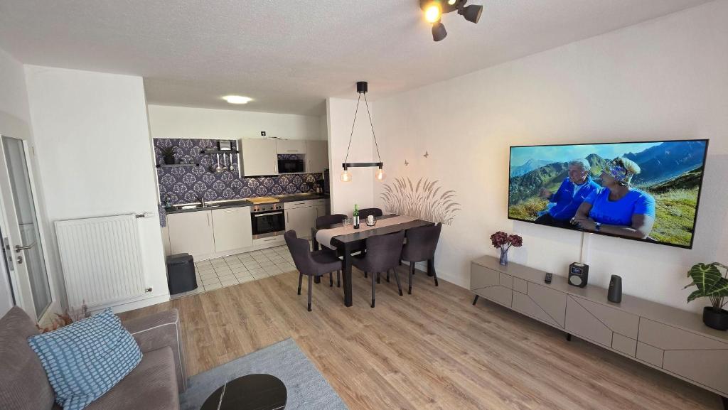 a living room with a dining table and a tv on the wall at WarenERleben in Waren